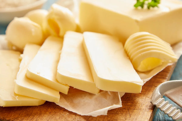 Sliced full-fat butter, a natural source of the essential fatty acid, C15:0, on a wooden cutting board.