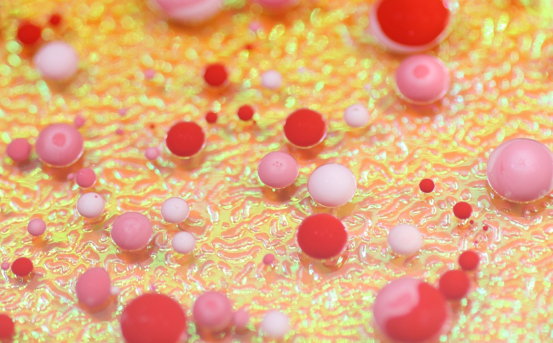 Colorful abstract pattern with pink and red spheres on a vibrant textured surface.