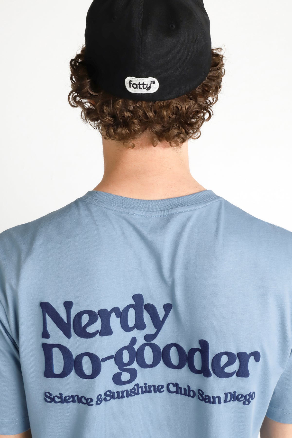 
                Man wearing a Nerdy Do Gooder t-shirt with black cap.