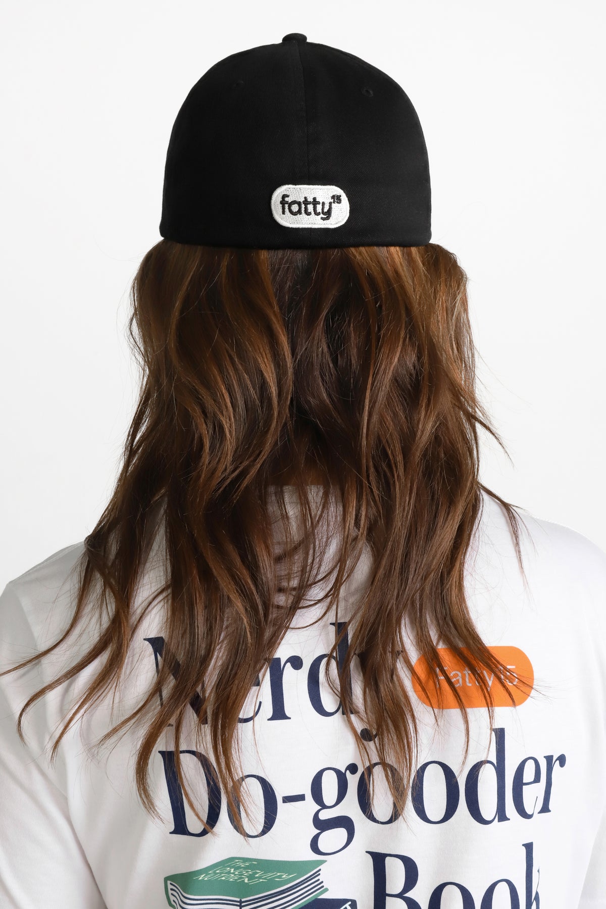 
                Person wearing a black cap and graphic T-shirt, facing away.