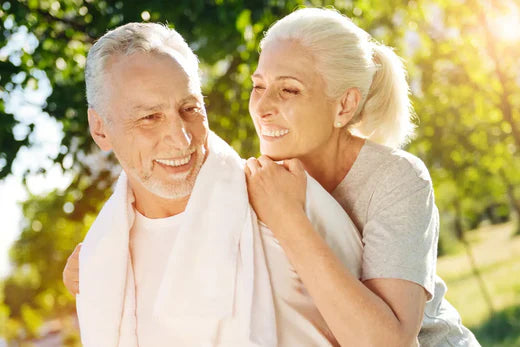 Elderly couple smiling in a sunny park.