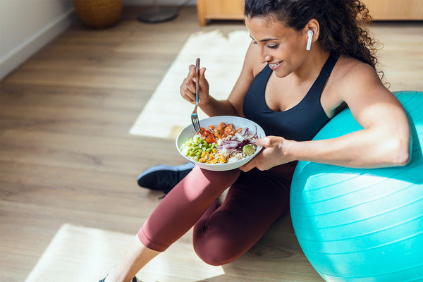 Woman eating healthy salad after workout with an exercise ball.