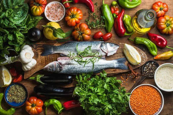 Fresh fish and colorful vegetables on a wooden table.