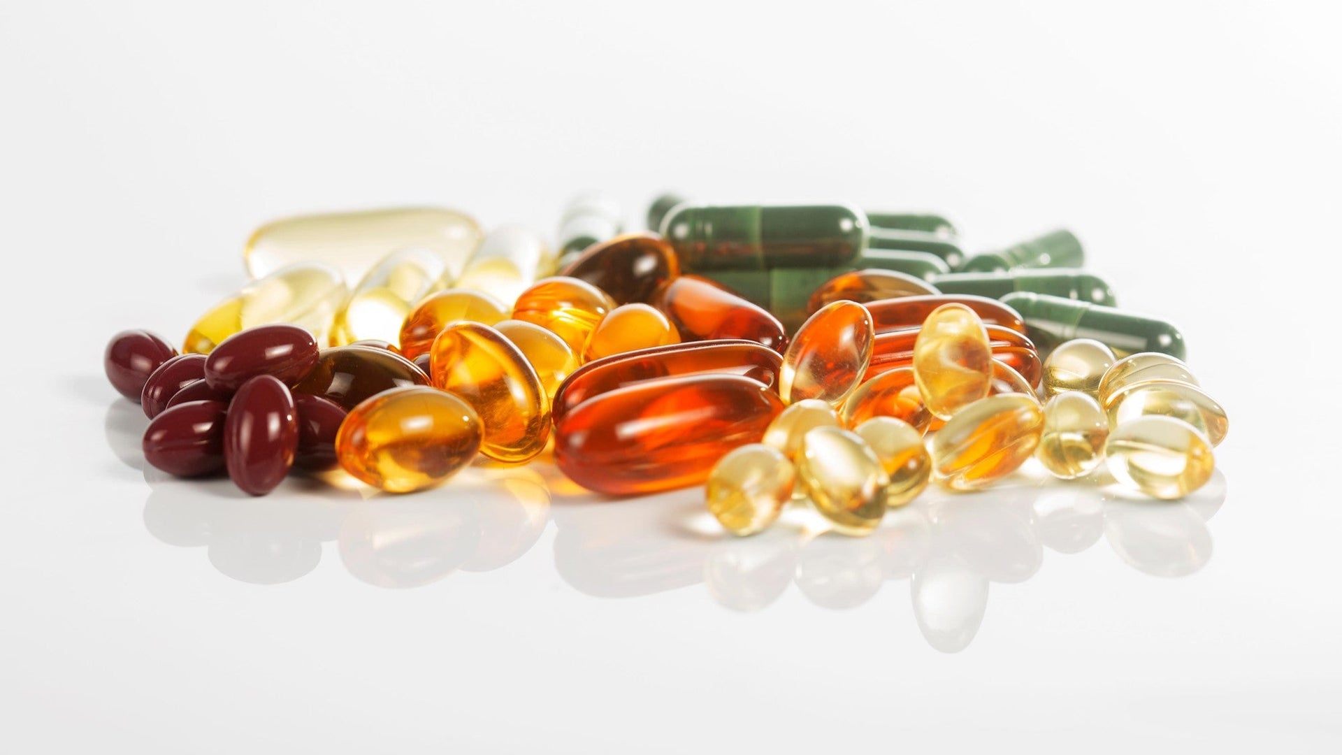 Assorted dietary supplements and vitamins in various colors on a white background.