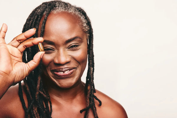 Smiling woman holding Fatty15 C15 supplement capsule.