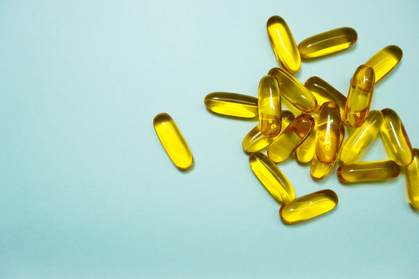 Yellow supplement capsules on a light blue background.