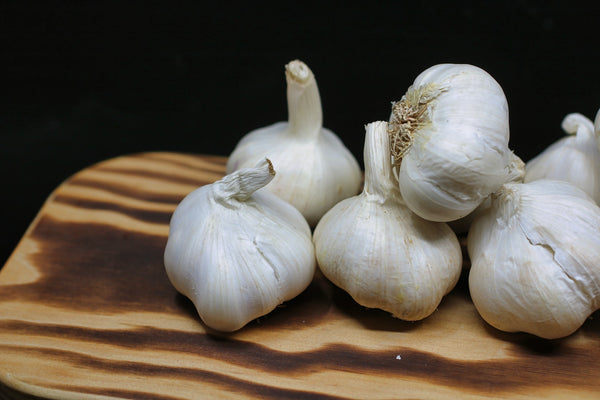 Garlic bulbs on a wooden cutting board.