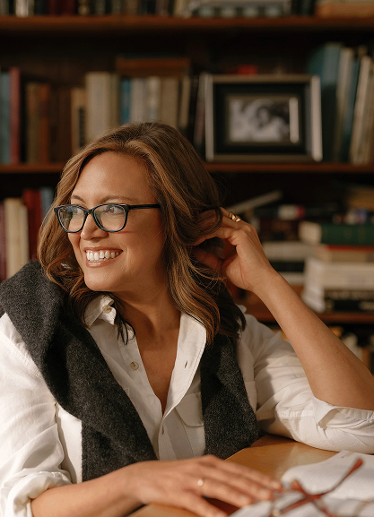Dr. Stephanie Venn-Watson smiling warmly in a cozy library setting.